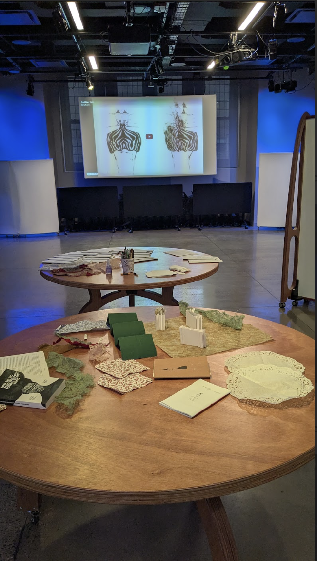 [a photo of two tables with assorted materials, and Freds dancing on a large screen.]